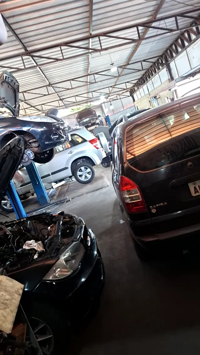 Interior da oficina Vila Car com carros de várias marcas em elevadores